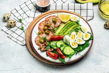shrimps, prawns, soft fried egg, fresh salad, tomatoes, cucumbers and avocado on a light background. Ketogenic diet breakfast. Keto, paleo lunch. Top view