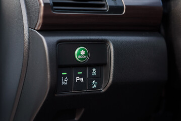 Green eco mode drive button in a modern car. Economic mode button, lane keep assist, parking...