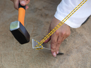 Hand of man holding a rubber mallet,hammering aluminium steel tent stakes pegs nail,fastening tent...