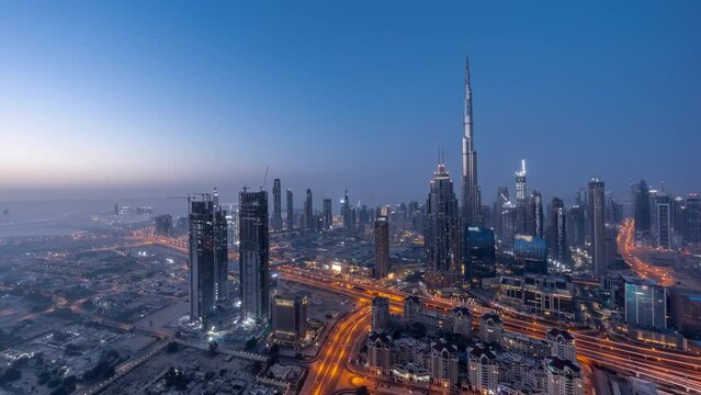 Aerial panoramic view of tallest towers in Dubai Downtown skyline night to day transition timelapse before sunrise. Financial district and business area in smart urban city. Skyscraper and high-rise