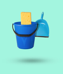 Levitating cleaning kit from a bucket, sponge and dustpan on a green background.