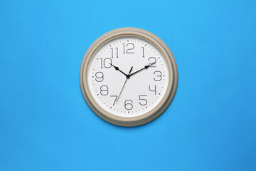 Large beige wall clock on a blue background. Minimal time concept.