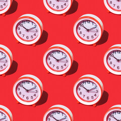 Seamless pattern of red and white alarm clocks on a red background.