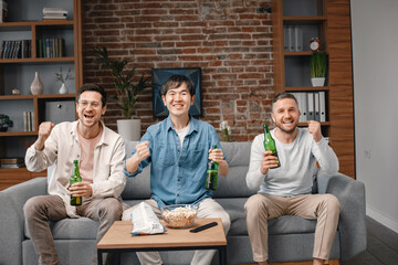 Front view of men watching a football game on tv and drinking a beer