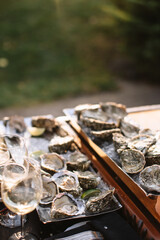 Opened and unopened oysters are served on ice with lime slices, with glasses of wine in the foreground.