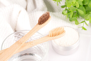 Bamboo toothbrushes with mineral toothpowder kaolin in alu container at white table against green...