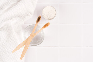 Top view on natural bamboo toothbrushes with mineral toothpowder kaolin in alu container at white table, copy space. Natural bath products, organic dentifrice