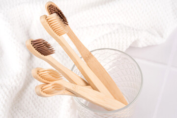 Natural biodegradable eco-friendly wooden toothbrushes with BPA free bristles in glass at white table. Natural bath products and zero waste concept, organic dentifrice. Mockup image