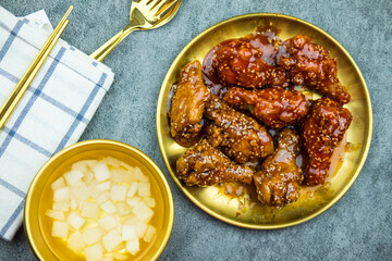 Crispy fried chicken wings with plain and spicy Korean sauce served with pickled radish