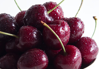 Red juicy sweet cherry in drops of water close-up on a light background