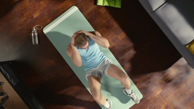 Top View Sport: Gorgeous Guy Doing ABS Crunches Lying on an Exericise Mat at Home. Muscular, Fit, Really Handsome Athletic Man Does Workout in His Apartment. Top Down Above Zoom out Shot