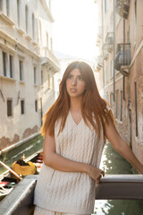Fototapeta na wymiar charming redhead woman in summer knitwear looking away in Venice on blurred background.