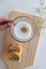 hand picking up a latte macchiato coffee and swiss roll, roll cake