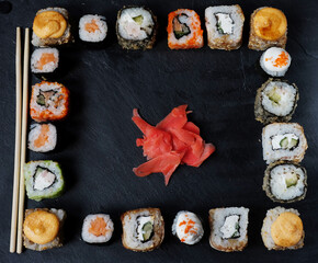 A variety of sushi with wooden desk on black slate background. Asian food frame. Dinner party.Top view.