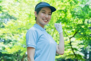ガッツポーズをするゴルフウェアを着た日本人女性