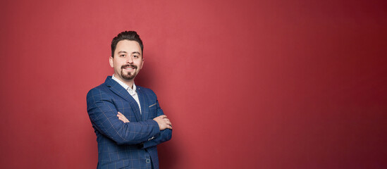 Portrait of happy smiling businessman looking at camera on red background