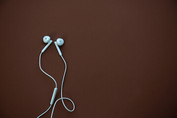 White earphones isolated on brown background with place for text, copy space