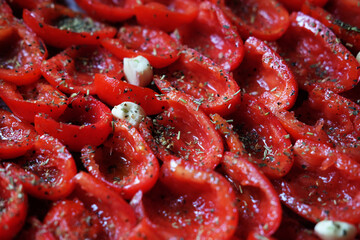Tomatoes lie on a baking sheet, ready to bake. Sun-dried tomatoes with garlic. - obrazy, fototapety, plakaty