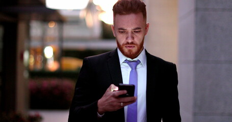 Corporate executive business man walking and looking at smartphone device