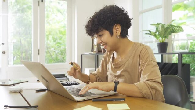 Portrait of business Asian woman, person using a credit card, shopping online at home or house, using a computer laptop notebook, technology device. People lifestyle.