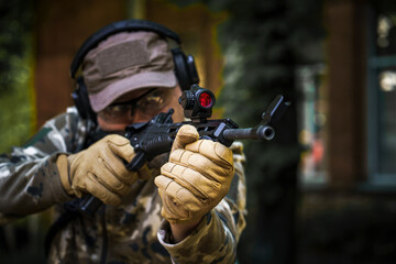Man with a gun in military uniform tactical hearing protector headset. Police training in shooting...