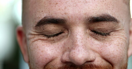 Obraz premium Contemplative young man closing eyes, taking a deep breath, feeling relaxed. close-up eyes portrait face