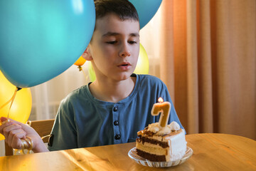 Happy boy celebrating his birthday. The boy makes a wish and blows out the candles on the cake