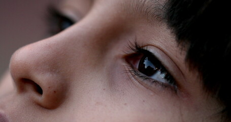 Close-up of child eyes looking up to sky in contemplation. Kid young boy face closeup eye thinking