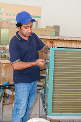 professional electrician checking air conditioner cooling condenser on the rooftop