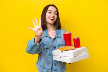 Young Ukrainian woman holding fast food isolated on yellow background happy and counting four with fingers