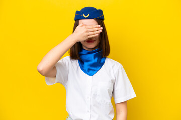 Airplane stewardess Ukrainian woman isolated on yellow background covering eyes by hands. Do not want to see something