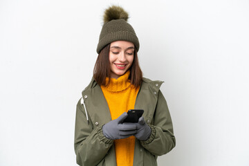 Young Ukrainian woman wearing winter jacket isolated on white background sending a message with the mobile
