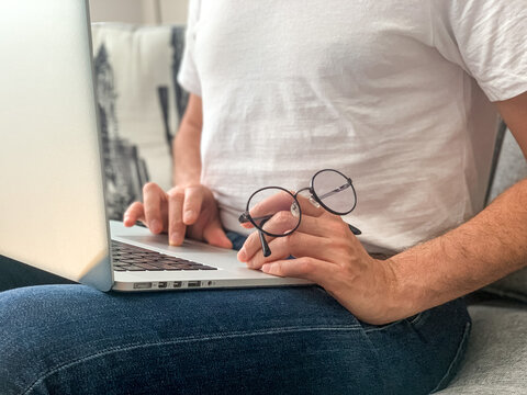 Man sitting on sofa before going to office using laptop making report checking business index home. IT specialist, code developer, python, coder