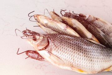Close-up of dried fish with drying hooks on a white table. Salty beer snack