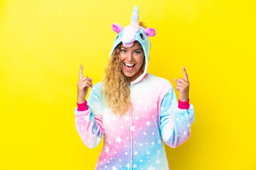 Girl with curly hair wearing a unicorn pajama isolated on yellow background pointing up a great idea