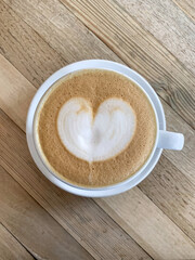 A cup of coffee latte On a wooden table. A mug of flat white coffee on a wooden background. Coffee art. Heart flower shape latte art. Copy space