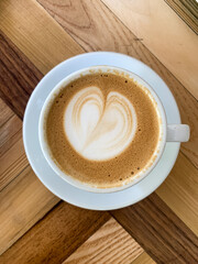 A cup of coffee latte On a wooden table. A mug of flat white coffee on a wooden background. Coffee art. Heart flower shape latte art. Copy space