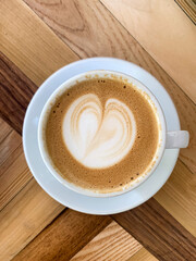 A cup of coffee latte On a wooden table. A mug of flat white coffee on a wooden background. Coffee art. Heart flower shape latte art. Copy space