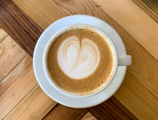A cup of coffee latte On a wooden table. A mug of flat white coffee on a wooden background. Coffee art. Heart flower shape latte art. Copy space