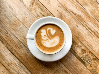 A cup of coffee latte on a wooden table. A mug of flat white coffee on a wooden background. Coffee art. Heart flower  shape latte art