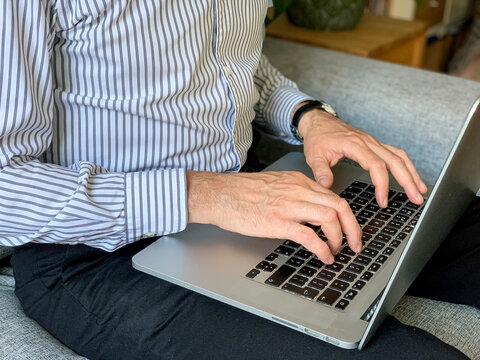 Man sitting on sofa before going to office using laptop making report checking business index home. IT specialist, code developer, python, coder