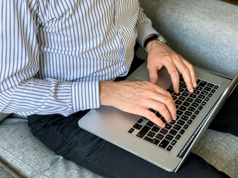 Man sitting on sofa before going to office using laptop making report checking business index home. IT specialist, code developer, python, coder