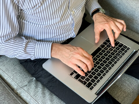 Man sitting on sofa before going to office using laptop making report checking business index home. IT specialist, code developer, python, coder