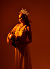 Close up portrait of beautiful red-haired woman wearing long flowing fantasy toga gown with golden...