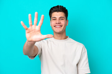 Naklejka premium Young handsome caucasian man isolated on blue bakcground counting five with fingers