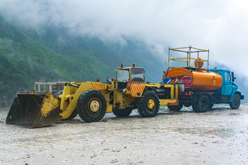 heavy road equipment for landslide raking stands by the roadside in a mountainous area during stormy weather