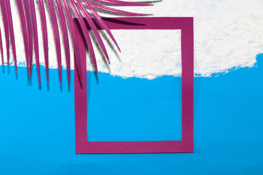 pink frame on the beach half in the water half on the sand with a pink palm leaf in the corner of the background, creative tropical design, copy space in the frame, idyllic vacation picture, minimal 