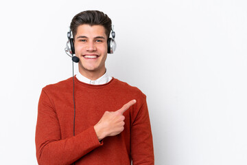 Telemarketer caucasian man working with a headset isolated on white background pointing to the side...