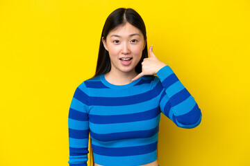 Young Chinese woman isolated on yellow background making phone gesture. Call me back sign