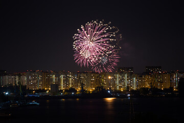 Fireworks over the houses in the city and reflection in the water